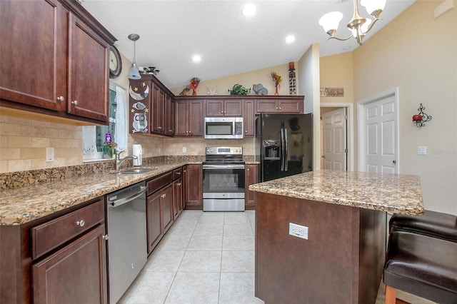 kitchen with pendant lighting, appliances with stainless steel finishes, sink, and vaulted ceiling