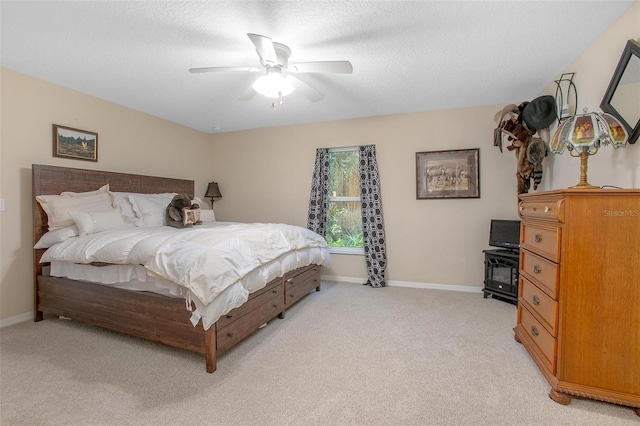 bedroom with ceiling fan, light colored carpet, and a textured ceiling