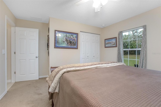 bedroom with ceiling fan, light colored carpet, and a closet