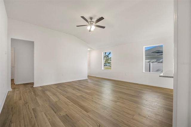 empty room with ceiling fan, lofted ceiling, and light hardwood / wood-style floors