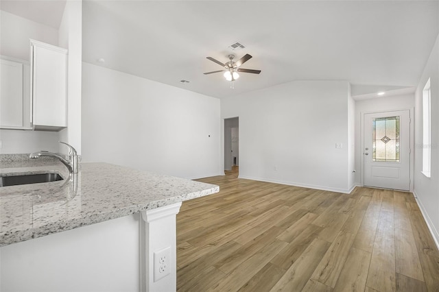 unfurnished living room featuring ceiling fan, lofted ceiling, sink, and light wood-type flooring