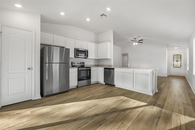 kitchen featuring lofted ceiling, sink, white cabinets, kitchen peninsula, and stainless steel appliances