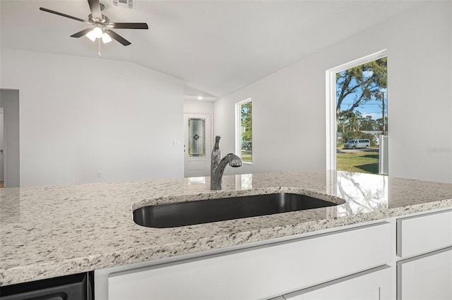 kitchen featuring lofted ceiling, sink, white cabinets, ceiling fan, and light stone counters