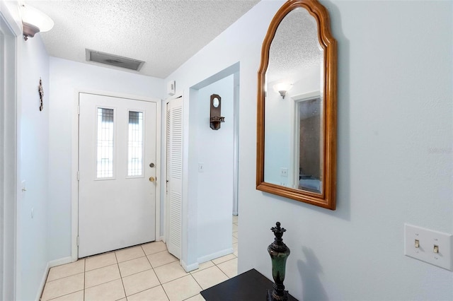 entryway with light tile patterned flooring and a textured ceiling