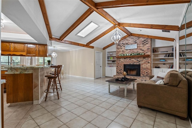 living room with a brick fireplace, a chandelier, built in features, and light tile patterned floors