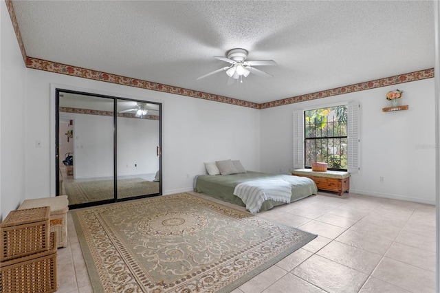 bedroom with light tile patterned floors, a closet, a textured ceiling, and ceiling fan