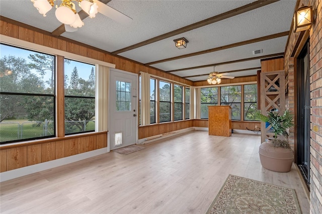 unfurnished sunroom featuring beamed ceiling and ceiling fan