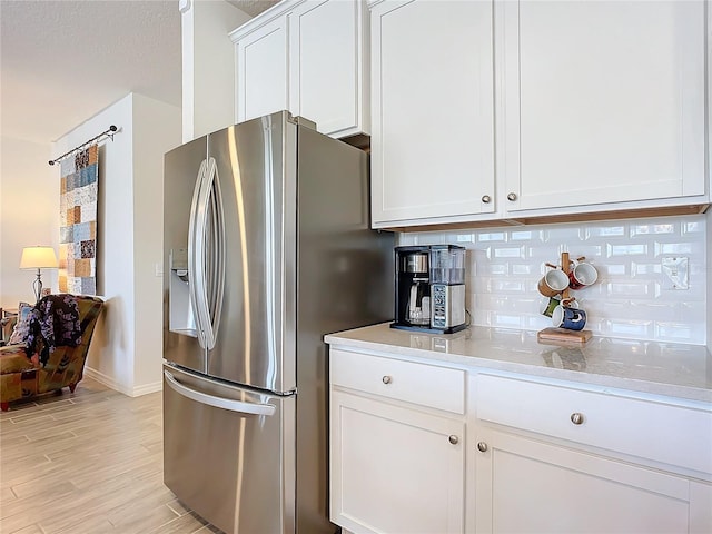 kitchen featuring white cabinetry, tasteful backsplash, stainless steel fridge with ice dispenser, a textured ceiling, and light wood-type flooring