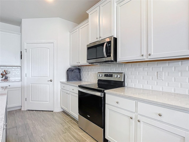 kitchen featuring tasteful backsplash, appliances with stainless steel finishes, white cabinets, and light stone counters