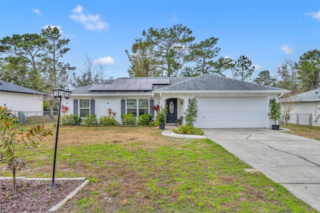 ranch-style house with a garage, a front lawn, and solar panels