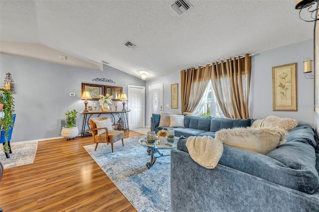 living room featuring lofted ceiling, hardwood / wood-style floors, and a textured ceiling