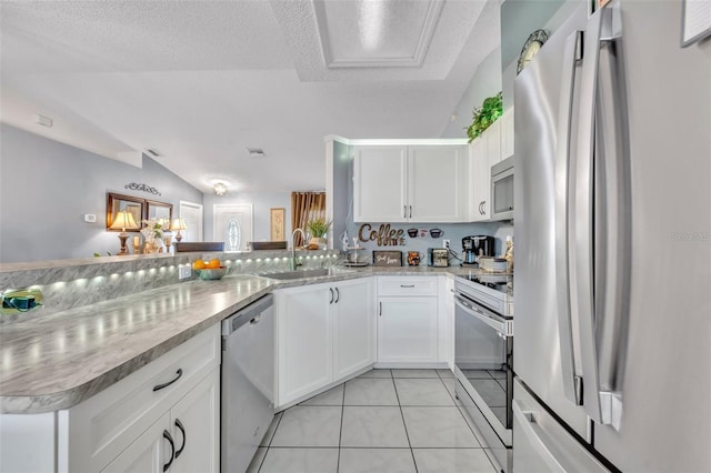 kitchen with white cabinetry, sink, light tile patterned floors, kitchen peninsula, and stainless steel appliances