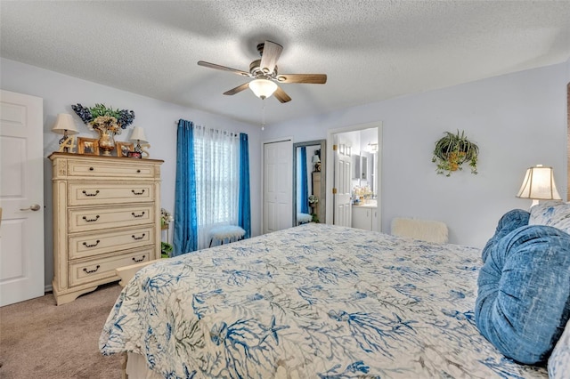 carpeted bedroom with ceiling fan, ensuite bathroom, and a textured ceiling