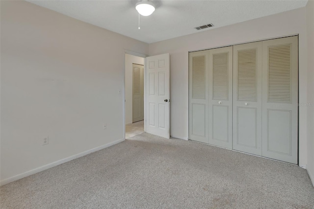 unfurnished bedroom with light colored carpet, a closet, and ceiling fan