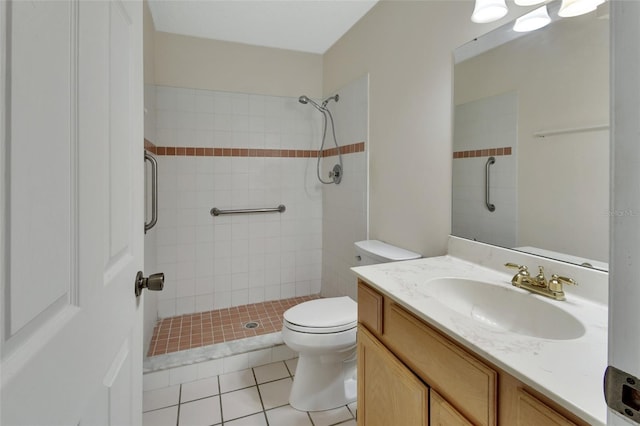 bathroom featuring vanity, tile patterned flooring, toilet, and a tile shower