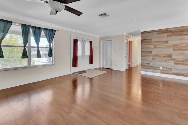 spare room with french doors, ornamental molding, wooden walls, ceiling fan, and hardwood / wood-style floors