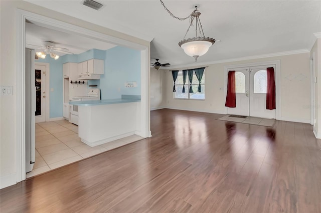 unfurnished living room with crown molding, ceiling fan, light wood-type flooring, and french doors