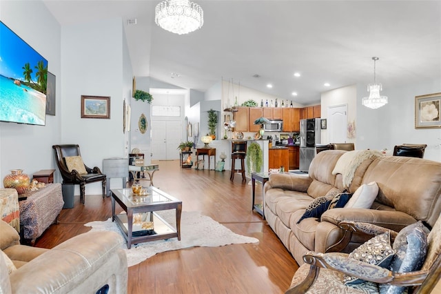 living room featuring lofted ceiling, light wood-type flooring, and an inviting chandelier