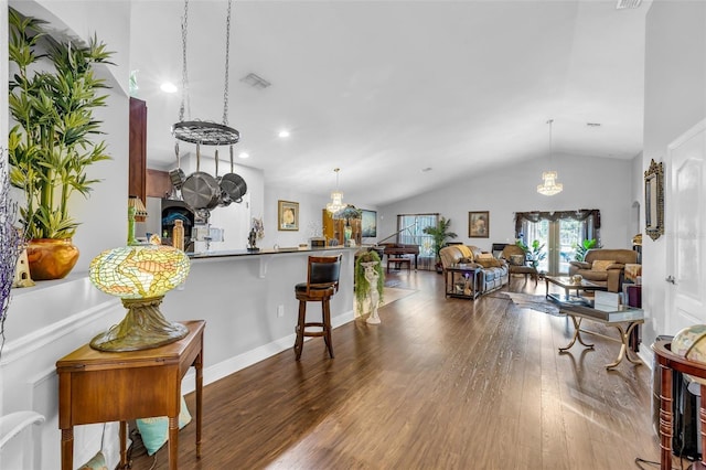 kitchen with lofted ceiling, a breakfast bar area, hardwood / wood-style floors, kitchen peninsula, and french doors