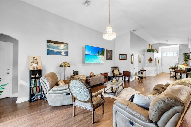 living room featuring lofted ceiling, wood-type flooring, and a chandelier