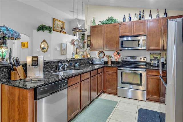 kitchen featuring sink, dark stone countertops, hanging light fixtures, light tile patterned floors, and stainless steel appliances