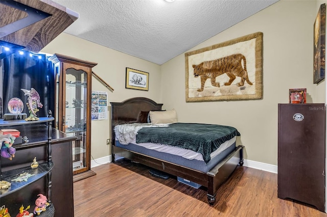 bedroom with hardwood / wood-style flooring, vaulted ceiling, and a textured ceiling