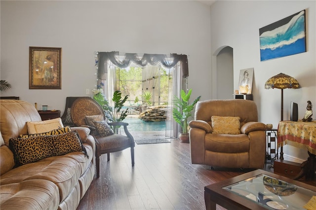 living room featuring a towering ceiling and dark hardwood / wood-style floors