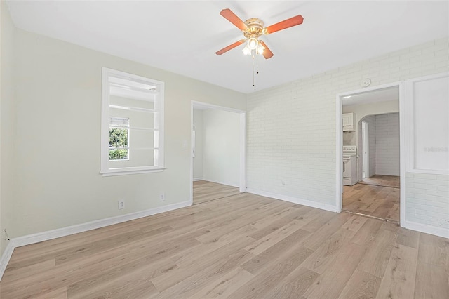 empty room featuring light wood-type flooring, ceiling fan, and brick wall