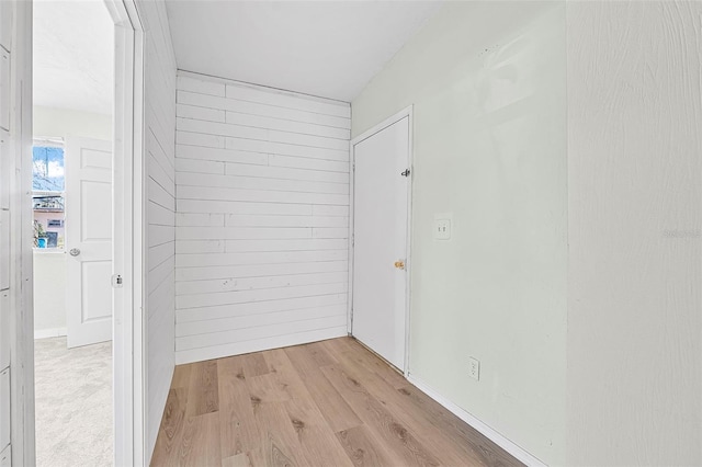 hallway featuring light hardwood / wood-style flooring and wood walls