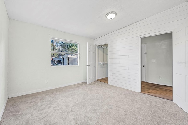 unfurnished bedroom featuring a closet, lofted ceiling, a spacious closet, and light carpet