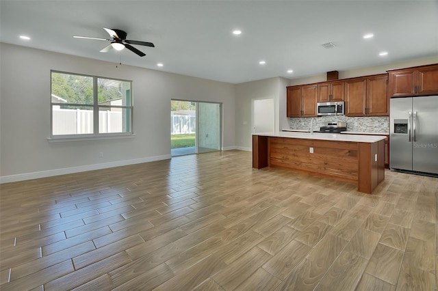 kitchen featuring a kitchen island, backsplash, ceiling fan, light hardwood / wood-style floors, and stainless steel appliances