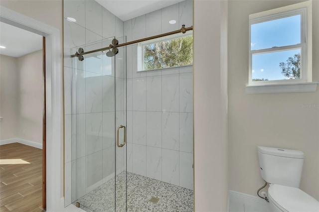 bathroom featuring hardwood / wood-style flooring, a shower with shower door, and toilet