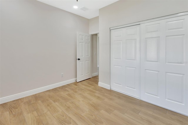 unfurnished bedroom featuring light hardwood / wood-style flooring and a closet