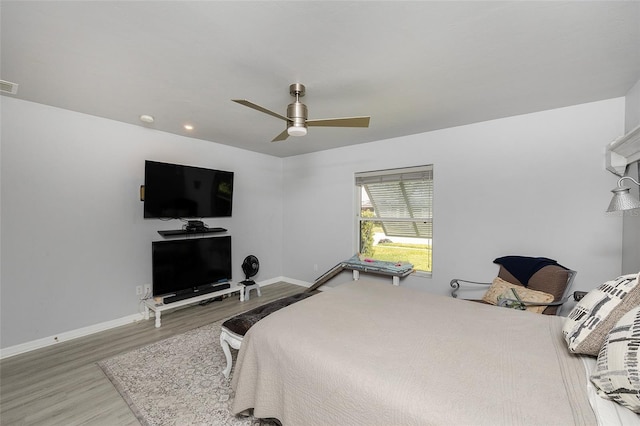 bedroom with a ceiling fan, visible vents, baseboards, and wood finished floors