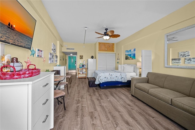 bedroom with visible vents, light wood-style flooring, and freestanding refrigerator