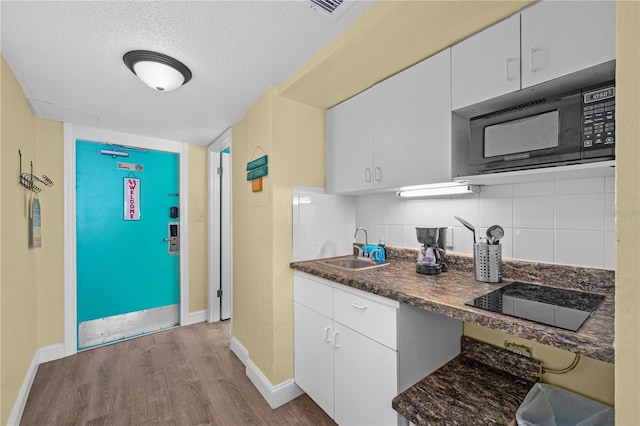 kitchen with a sink, backsplash, black appliances, and wood finished floors