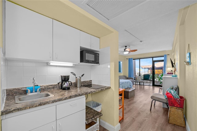 kitchen with black appliances, wood finished floors, tasteful backsplash, and a sink