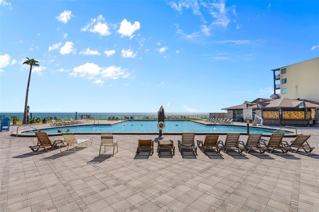 community pool with a water view and a patio area