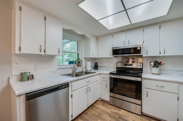 kitchen featuring appliances with stainless steel finishes, sink, white cabinets, and light hardwood / wood-style floors