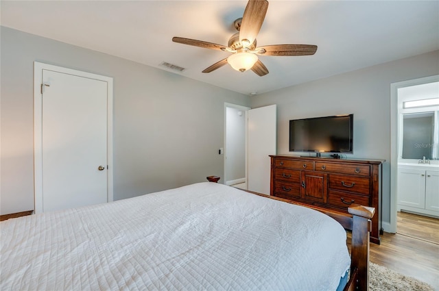 bedroom with ensuite bathroom, ceiling fan, and light hardwood / wood-style flooring