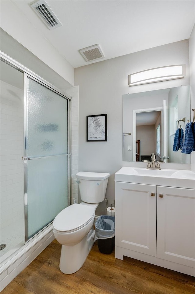 bathroom with vanity, wood-type flooring, a shower with door, and toilet