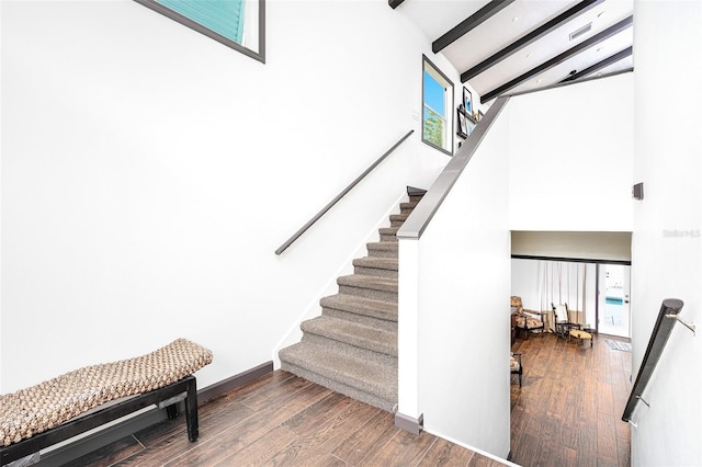 stairway with beamed ceiling, wood-type flooring, and high vaulted ceiling