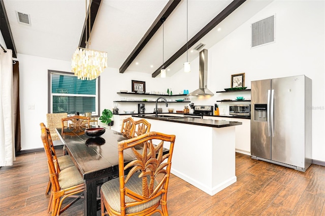 kitchen featuring appliances with stainless steel finishes, decorative light fixtures, sink, wall chimney range hood, and beam ceiling