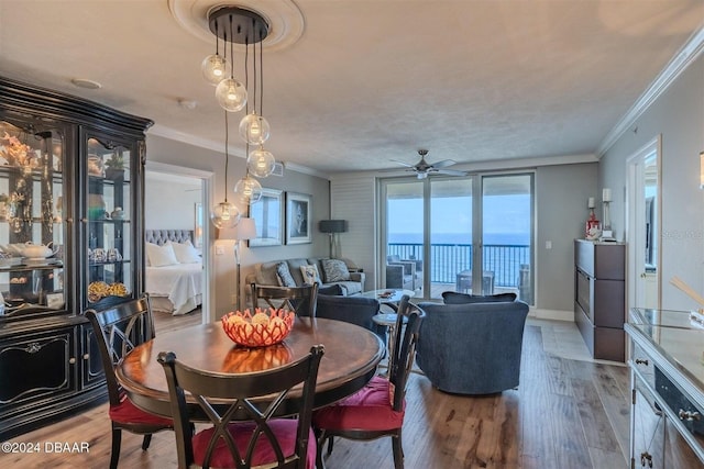 dining room with crown molding, ceiling fan, hardwood / wood-style floors, a water view, and a textured ceiling