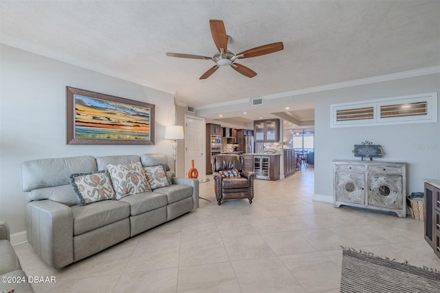 tiled living room featuring a textured ceiling, ornamental molding, and ceiling fan