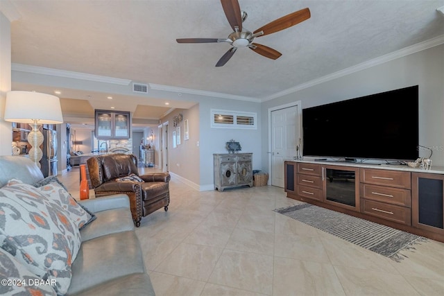 living room featuring light tile patterned floors, crown molding, a textured ceiling, and ceiling fan