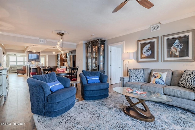 living room with crown molding, ceiling fan, and light wood-type flooring