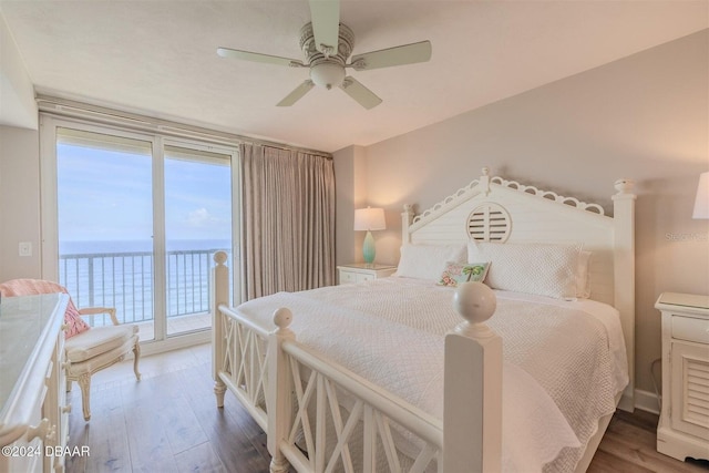 bedroom with multiple windows, dark hardwood / wood-style flooring, access to outside, ceiling fan, and a water view