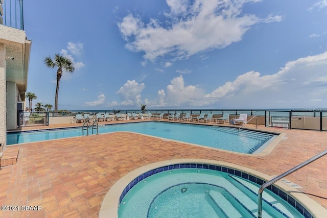 view of swimming pool featuring a community hot tub and a water view