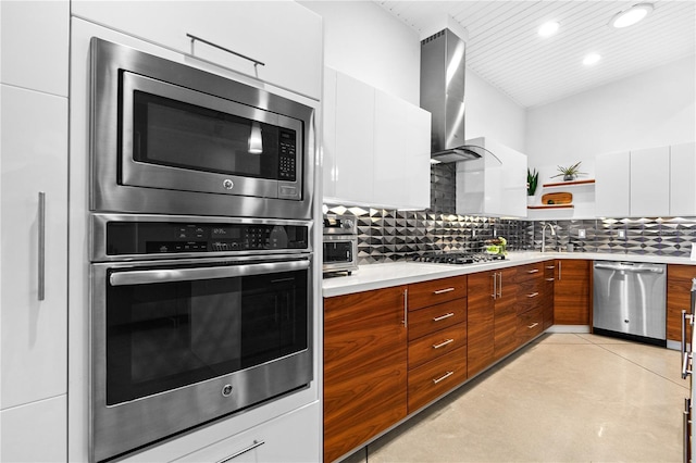 kitchen with wall chimney exhaust hood, sink, white cabinetry, stainless steel appliances, and decorative backsplash